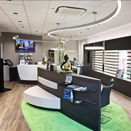 Modernes Optiker-Geschäft mit stilvollem Empfangsbereich, Brillenauswahl und Beratungstheke.