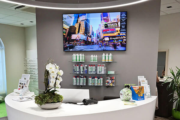 Moderner Empfangsbereich einer Augenarztpraxis mit Pflegeprodukten und Dekoration.